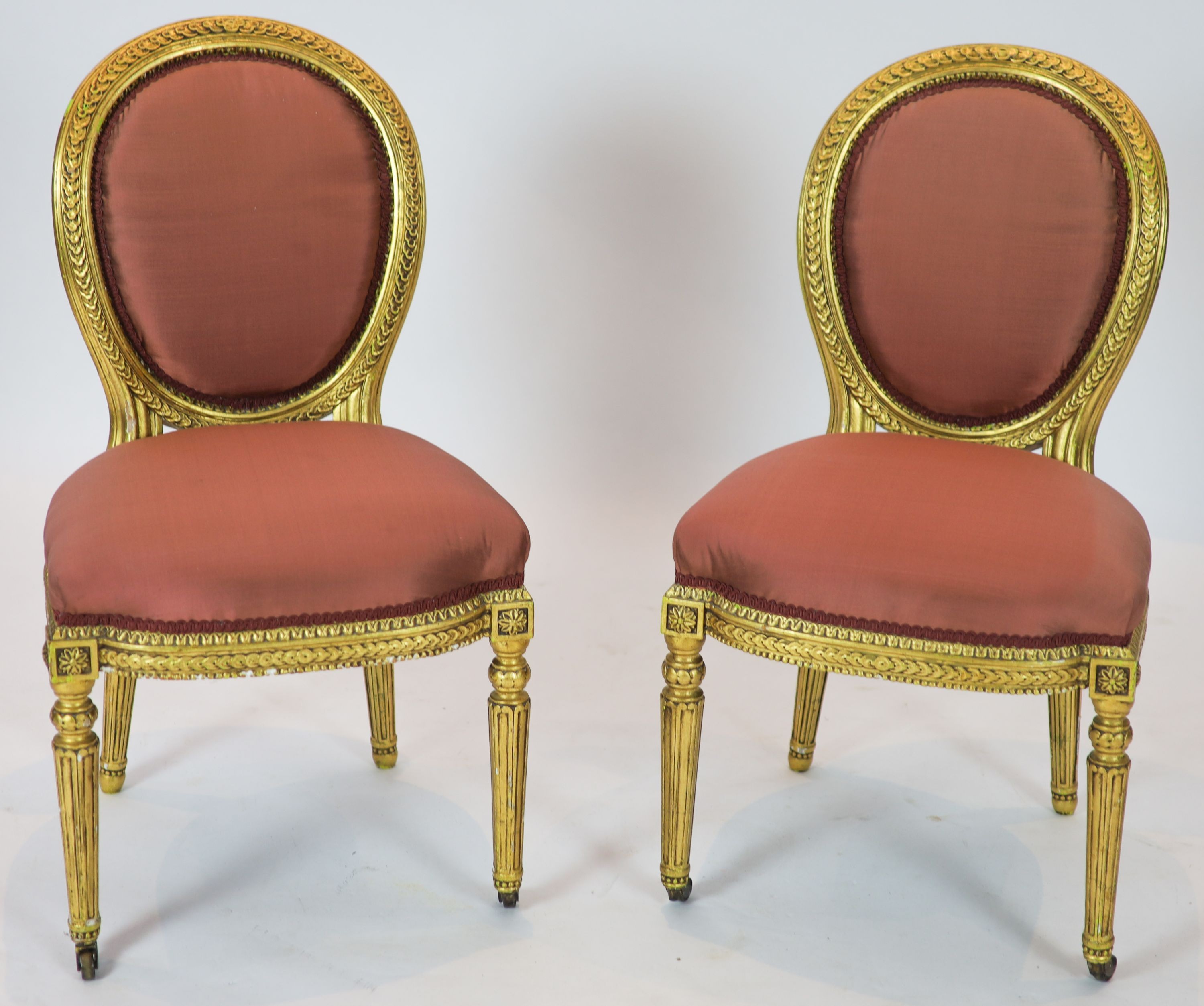 A pair of 19th century Louis XV style giltwood framed side chairs, with oval carved backs, on turned and fluted legs